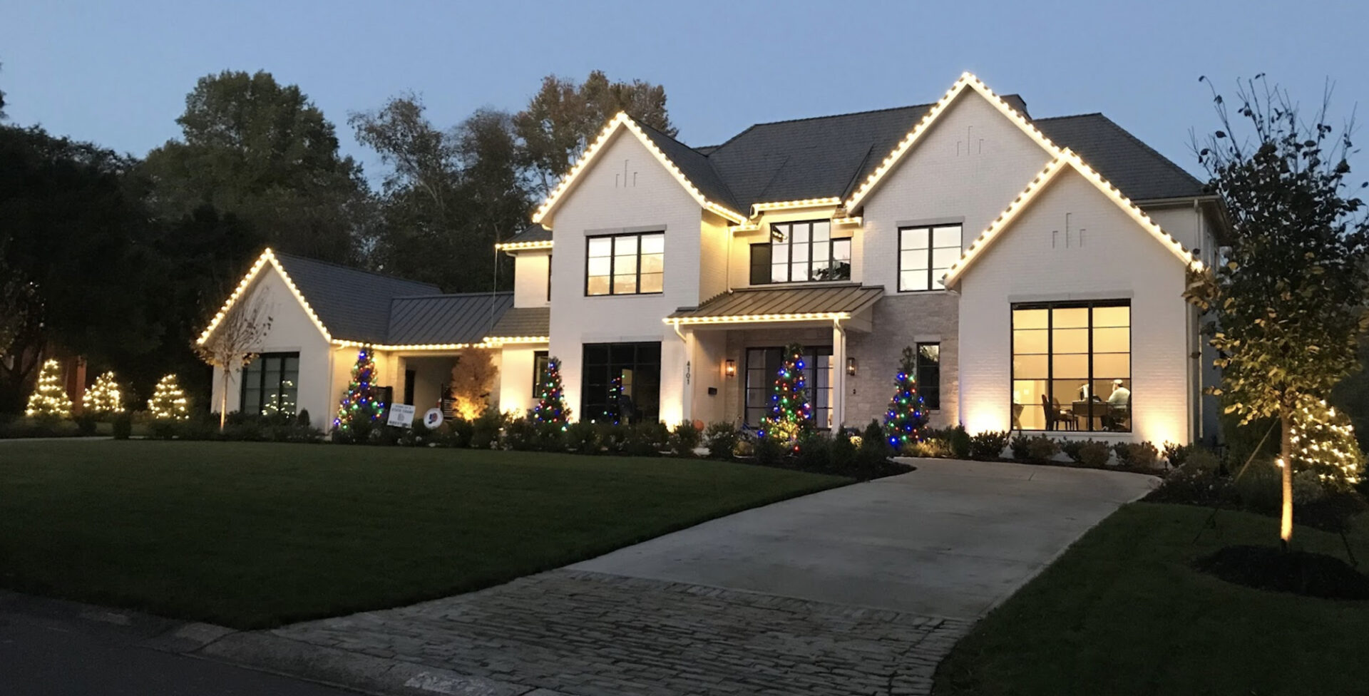 A modern white home with bright white holiday lights.